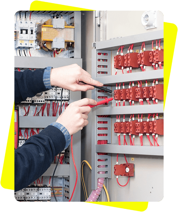 A technician is using a screwdriver on an electrical panel with multiple red and white wires.